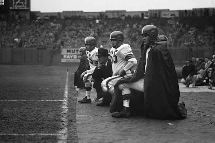 On Dec. 8, 1953, Cleveland Browns coach Paul Brown is flanked by (from l. to r.) halfback Ray Renfro, guard Chuck Noll (65) and halfback Billy Reynolds. (AP)